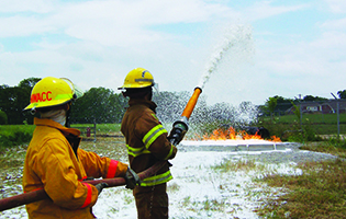 Two Fire Science students holding a hose pointed towards a fire