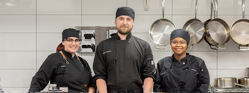 three culinary students smiling at the camera