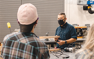 Man wearing mask teaches students about lumber