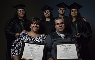 Latino family smiling and holding college degrees