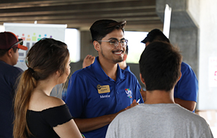 Male student smiling and talking to other students