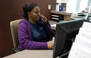 Black female sitting at a desk talking on an office phone