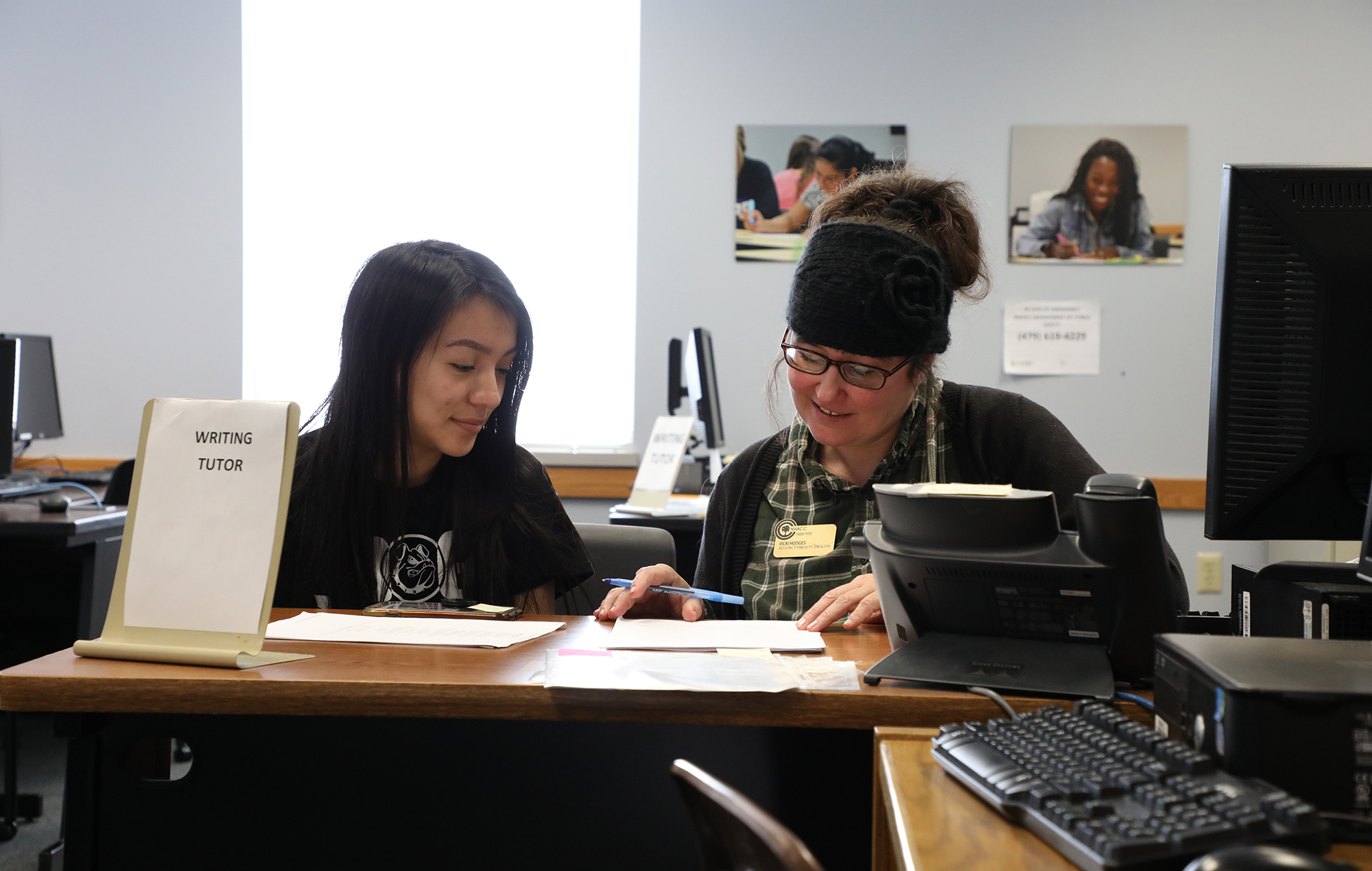 Mature woman tutoring a young female student in writing